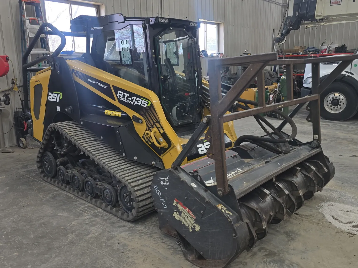 ASV RT-135 compact track loader with drum mulching head parked in the shop
